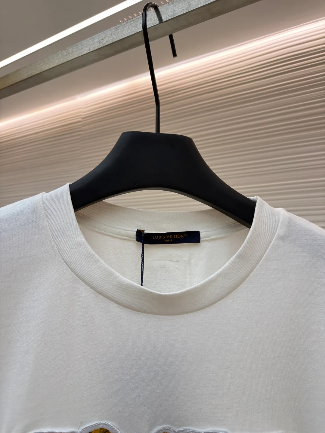 LOUIS VUITTON cotton round neck embroidered Vuitton signature logo short sleeves ●Original version: purchased and developed for 12300 ●Item number: 1682272-A10 ●Fabric: cotton fabric ●Technology: embroidery production ●Color: white ●Version: fitted version ●Weight: about 270 grams ●Size: S-M-L-XL ●Description: This white short-sleeved T-shirt is made of high-count combed cotton fabric and has been treated with pre-washing technology. It has a soft and skin-friendly touch and is not easy to deform. The silhouette of the shirt is a loose shoulder design, which meets the needs of modern casual wear. The core decoration area on the chest uses hand-beading and bronzing technology, and uses metallic gold sequins and embroidery threads intertwined to outline a three-dimensional letter pattern. The sequins are layered and inlaid, and each one is manually positioned and fixed by craftsmen to ensure a regular texture and uniform gloss. The edges of the letters are sewn with matte silk thread to form a visual contrast between gold and matte, while reinforcing the decorative structure to avoid falling off during wear. The neckline uses double-needle hemming technology and is matched with ribbed cuffs of the same fabric. It is durable and fits the neck. The overall craftsmanship combines handicraftsmanship with modern clothing technology, and the details show exquisite texture. The overall wiring is straight and delicate, the fabric is comfortable and soft, and the color is consistent without color difference. It can be matched with the same style to create a fashionable look and control various occasions. Customized accessories, complete with three standards, same style for men and women!